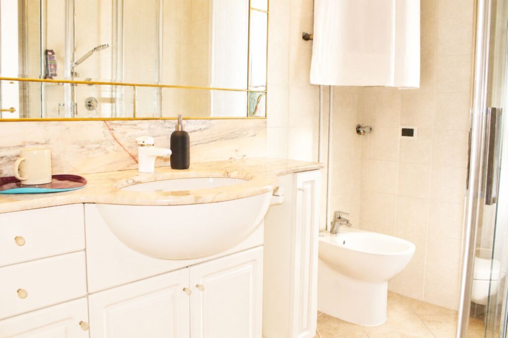 Bagnetto di Casa della Torre con lavabo, specchio, bidet e finiture in marmo chiaro