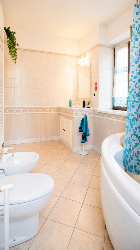 Bagno luminoso con vasca, lavabo, bidet e finiture in tonalità chiare.