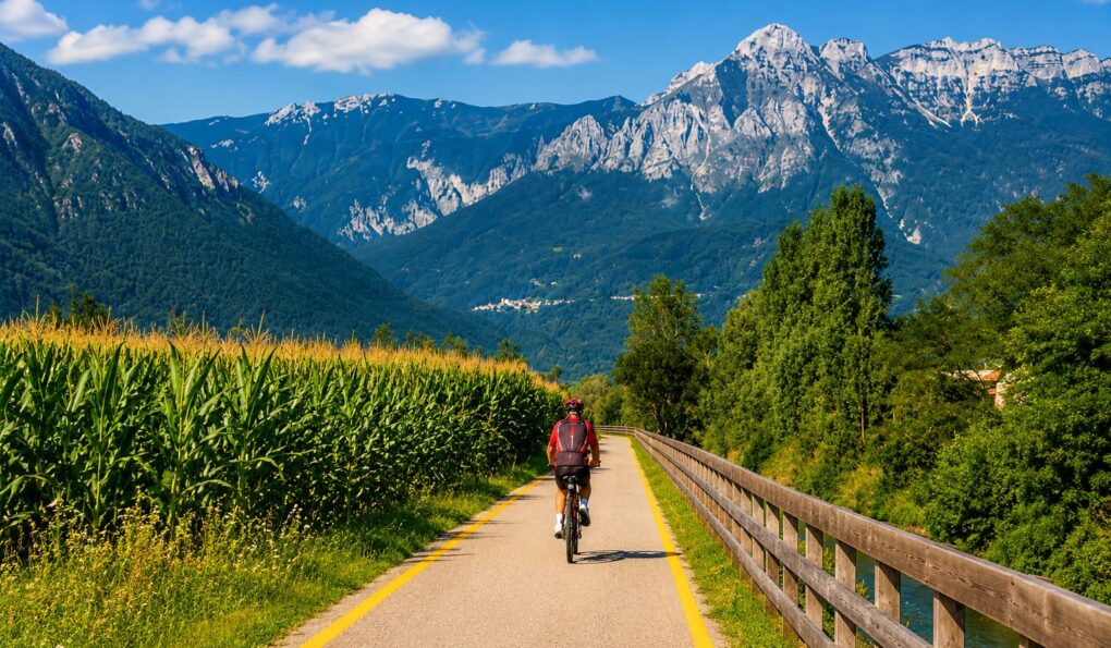 Ciclista lungo una pista ciclabile tra campi e montagne vicino a Levico Terme
