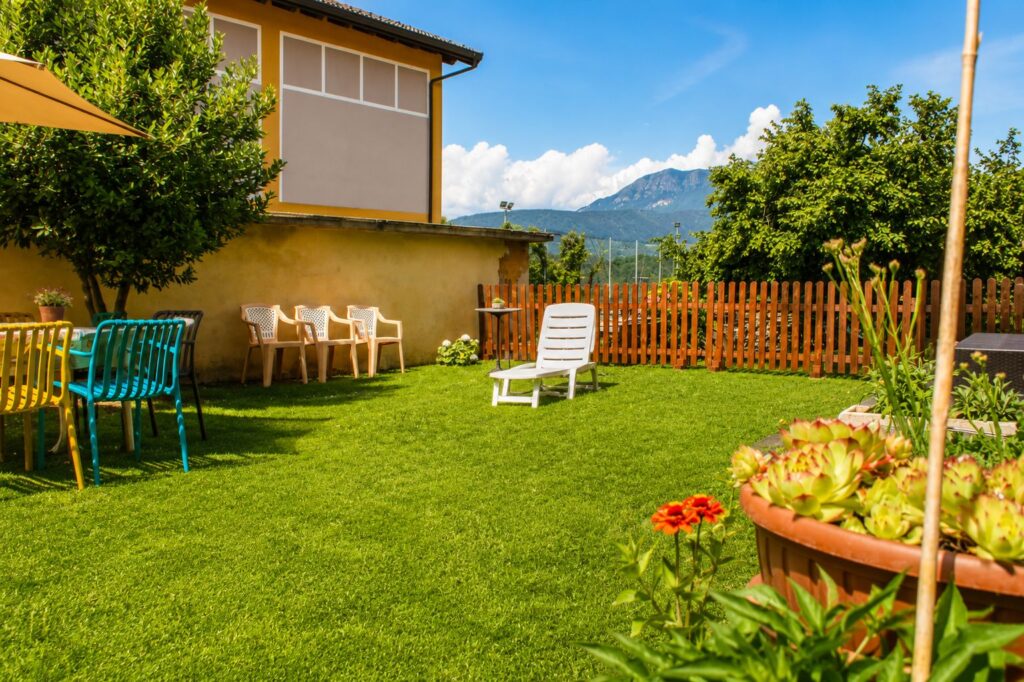 Giardino della Casa della Torre con sedie, lettino prendisole, piante e vista sulle montagne.