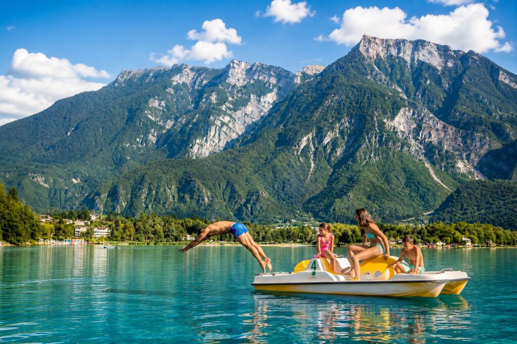 Famiglia in pedalò sul lago di Levico con le montagne del Trentino sullo sfondo